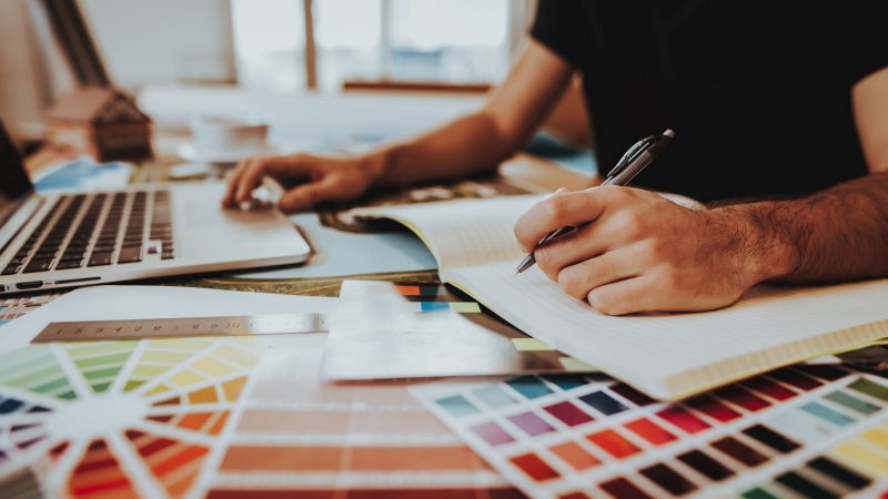 Person sketching a design into a sketchbook.