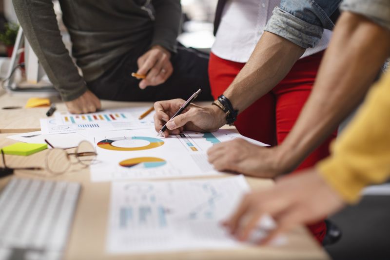 People sitting around a desk analyzing spreadsheets.
